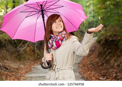 Beautiful girl with umbrella checking for rain