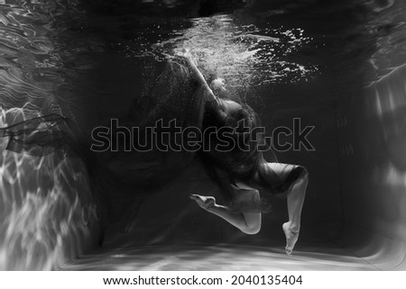 Beautiful girl underwater in the pool. Black and white photography, creative and mystical