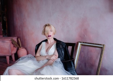 Beautiful Girl In An Unusual Image Of The Bride. The Bride In A Delicate Dress And Rude Black Boots And A Black Leather Jacket.