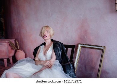 Beautiful Girl In An Unusual Image Of The Bride. The Bride In A Delicate Dress And Rude Black Boots And A Black Leather Jacket.