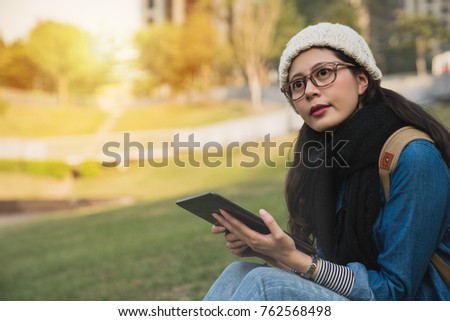 beautiful girl using the e-learning ebook with digital tablet and look away in winter park on a sunny day.