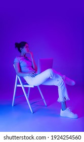 Beautiful girl using laptop isolated multicolored background in neon light 