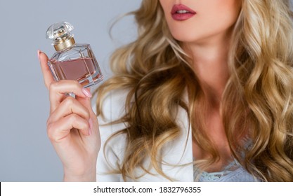 Beautiful girl using perfume. Woman with bottle of perfume. Woman presents perfumes fragrance. Perfume bottle woman spray aroma. Woman holding a perfumes bottle.