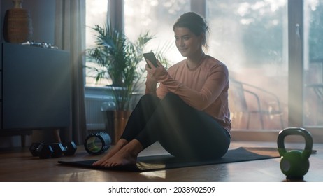 Beautiful Girl Using Smartphone After Fitness Workout At Home. Authentic Plus Size Woman Using Fitness Tracker, Yoga Exercises Application, Browsing Online Health Articles, Posting On Internet