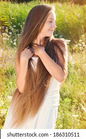 Beautiful Girl with very long Hair at the Meadow on sun light  in Countryside. Healthy lifestyle