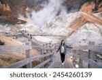 Beautiful girl with view during Authum and Steam rising in the Hell Valley or Noboribetsu Jigokudani, Shikotsu-Toya National Park, Hokkaido, Japan.