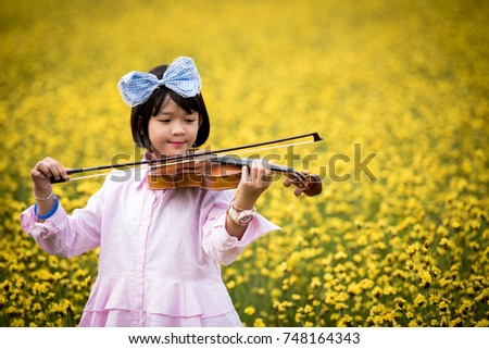 Beautiful girl with violin in yellow field