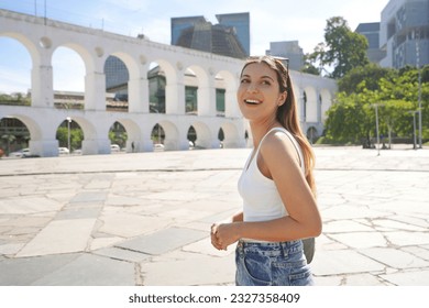 Beautiful girl walking in Lapa neighborhood with Carioca Aqueduct (Arcos da Lapa) in Rio de Janeiro, Brazil