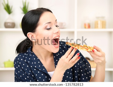 Beautiful girl wants to eat delicious pizza on kitchen background