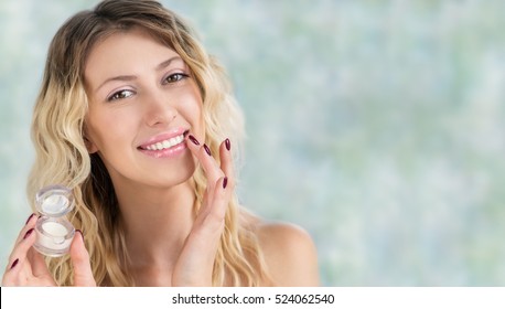 Beautiful Girl With Wavy Hair Cares Of Her Lips. Young Blonde Woman Applying Make-up Cosmetic SPA Product Lip Balm Or Gloss For Hydration, Smoothing And Skin Rejuvenation. Makeup, Wellness Or Skincare