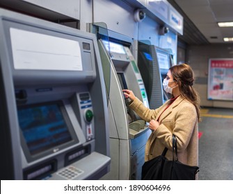 Beautiful Girl Wearing Protective Medical Mask And Fashionable Clothes Uses ATM Machine For Money.New Normal Concept During Pandemic Corona,covid19.