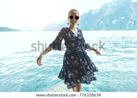 beautiful girl wearing sunglass posing relaxing in vacation standing on floor wood with lake and mountain