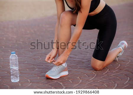 beautiful girl while running ties laces in sneakers