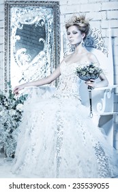 Beautiful girl in white dress in the image of the Snow Queen with a crown on her head. Picture taken in the studio with decorations.