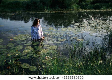 beautiful girl in a white dress in a swamp with water lilies