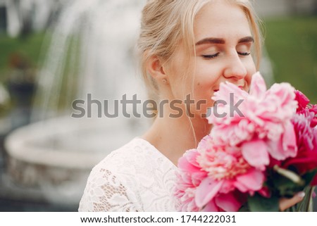 Beautiful girl in a white dress. Woman in a summer park. Lady with a red flowers