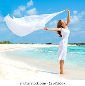 Beautiful Girl With White Scarf Jumping on The Beach. Travel and Vacation. Freedom Concept. Full length portrait