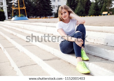 beautiful girl in a white T-shirt and jeans sitting on a stone staircase. mockup.