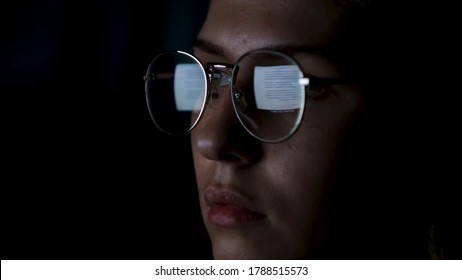 Beautiful Girl Works On Internet With The Reflection Of A Monitor Inside Glasses. Concept. Close Up Of Woman Face Wearing Glasses With The Screen Reflected In Lenses Isolated On Black Background.