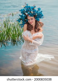 Beautiful Girl In Wreath Of Flowers At Lake. Portrait Of Young Beautiful Woman. Young Pagan Girl Conduct Ceremony On Midsummer. Earth Day