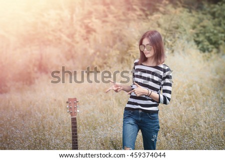 Beautiful girls stand  with your guitar on the grass with sunrise.