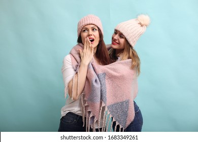 Beautiful girls in a studio. Stylish women on a blue background. Ladies in winter hats and scarfs.
