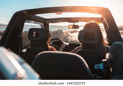 Beautiful girls and young people traveling with jeep car in a sunset in a beach landscape - Powered by Shutterstock