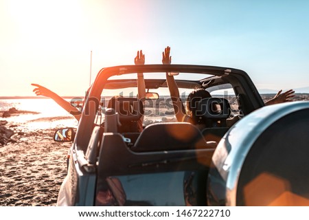 Beautiful girls and young people traveling with jeep car in a sunset in a beach landscape