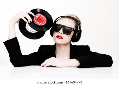 Beautiful glamorous sensual disc jockey wearing sunglasses and headphones and holding two vinyl records in her head, isolated on white