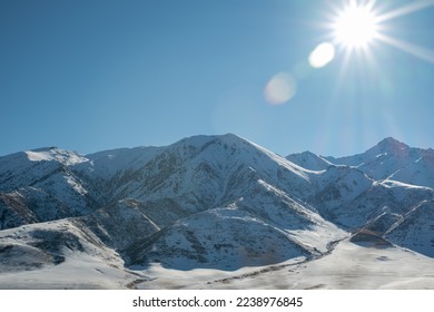 beautiful glare of the sun illuminates snowcapped mountains. panoramic view. Winter. beautiful clear blue sky in daylight. impressive view of the mountain peaks - Shutterstock ID 2238976845