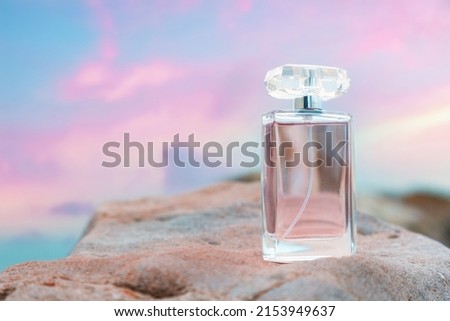 Beautiful glass bottle with purple perfume on white rock. Copy space. Concept of luxe perfumery and cosmetics.