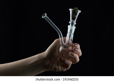 beautiful glass pipe with marijuana on black background, with woman's hand