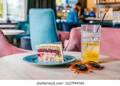 Beautiful Glass Of Yellow Passionfruit Lemonade And Piece Of Poppy Cake With Brown Sunglasses On The Wooden Table. Flatlay Style, Spotted On The City Cafe. Summer Brunch Situation.