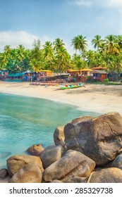 Beautiful Goa province beach in India with fishing boats and stones in the sea 