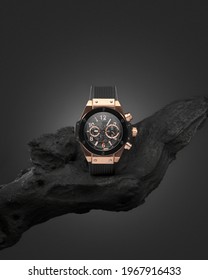 Beautiful gold men's watch with a black strap on a wooden stand, on a gray background. Beautiful gold watch. A luxury brand watch - Shutterstock ID 1967916433
