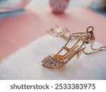 A beautiful gold necklace featuring a high-heeled shoe pendant, with the chain elegantly draping. The bright pink background enhances the charm of the piece, making it perfect for fashion or jewelry-t