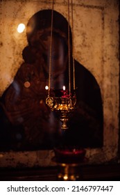 Beautiful golden figured censer thurible with burning candle hanging with chain in front of old icon of Divine Mother in orthodox church. Faith in God, religion, ceremony, praying, Christianity.