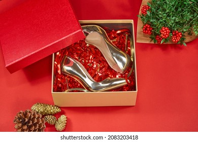 Beautiful golden high-heeled shoes  in a Christmas Gift Box in a red background