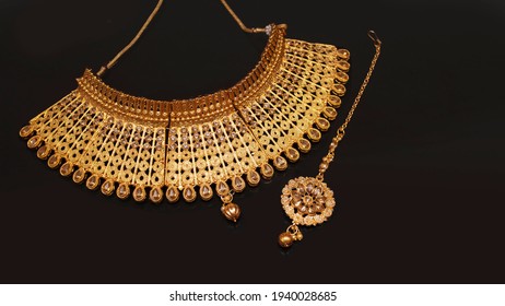 A beautiful golden necklace with stone and diamonds on dark black background.