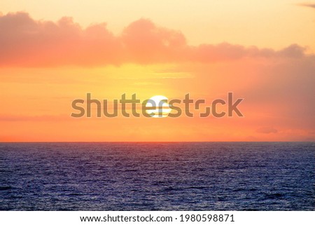 Beautiful golden orange sunset over the ocean. The sun sets turning the sky yellow, orange e red tones.