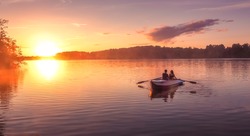 A Beautiful Golden Sunset On The River. Lovers Ride In A Boat On A Lake During A Beautiful Sunset. Happy Couple Woman And Man Together Relaxing On The Water. The Beautiful Nature Around. 