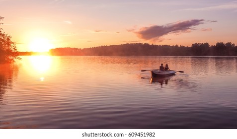 A beautiful golden sunset on the river. Lovers ride in a boat on a lake during a beautiful sunset. Happy couple woman and man together relaxing on the water. The beautiful nature around.  - Powered by Shutterstock