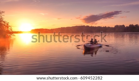 A beautiful golden sunset on the river. Lovers ride in a boat on a lake during a beautiful sunset. Happy couple woman and man together relaxing on the water. The beautiful nature around. 