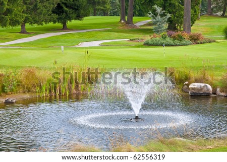 Beautiful golf place with gorgeous green, pond and fountain.