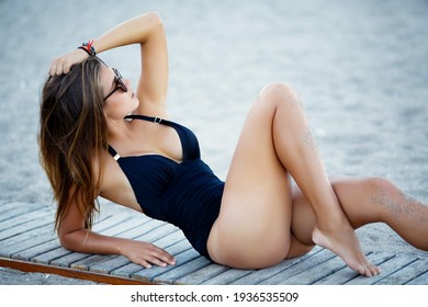 Beautiful gorgeous tanned woman bikini model at tropical sand beach. Young glamour girl in swimsuit at pool outdoors. Perfect body lingerie model at island resort. Fitness bikini summer portrait