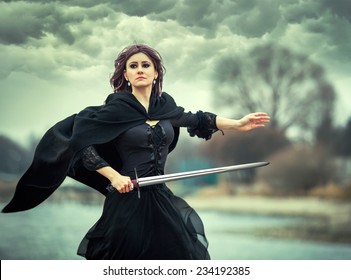 The beautiful gothic girl holds a sword in a hand