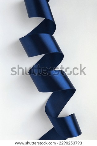 Beautiful graceful curls of a dark blue satin ribbon on a white background