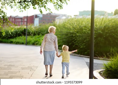 Beautiful Granny And Her Little Grandchild Walking Together In Park. Grandma And Grandson Holding Hands. Family Time