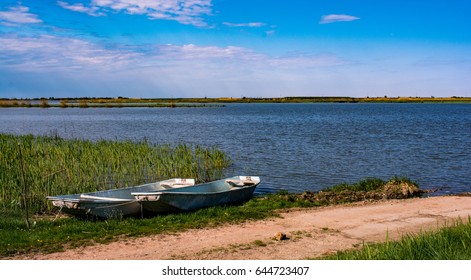 Beautiful Grass And Two Old Boats That Beautifies The Landscape Near Fishpond With Blue Sky, With Almost Pink Clouds. Where Dirty Road End's There Is A Lake And Boat. Serbia Countryside Landscape. 