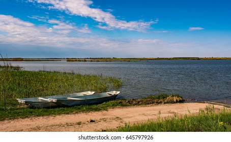 Beautiful Grass And Two Old Boats That Beautifies The Landscape Near Fishpond With Blue Sky, With Almost Pink Clouds. Where Dirty Road End's There Is A Lake And Boat. Serbia Countryside Landscape.